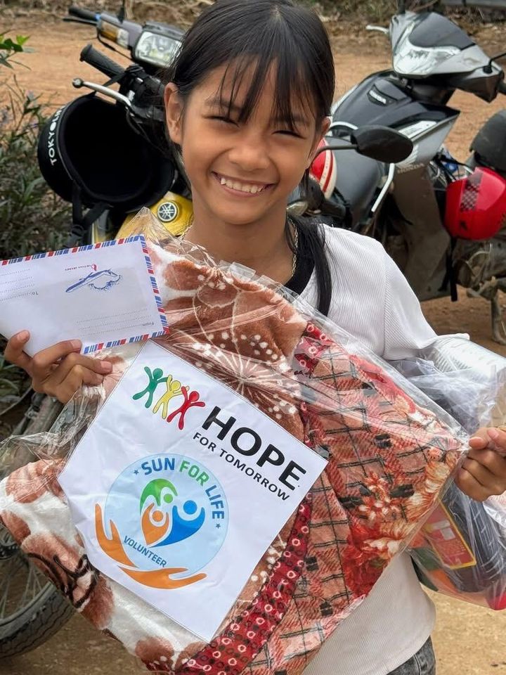 A smiling girl holding a HOPE and Sun For Life gift package